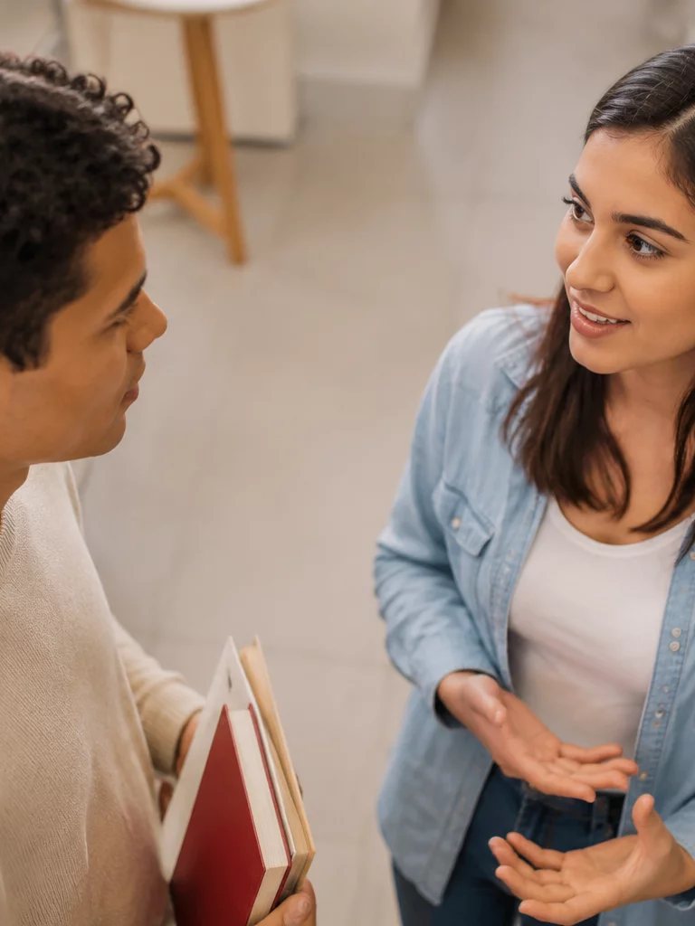 Duas participantes conversando de pé no corredor entre prateleiras de livros