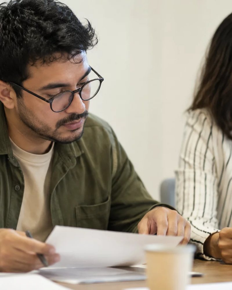Grupo sentado numa sala clara enquanto uma pessoa defende um ponto de vista